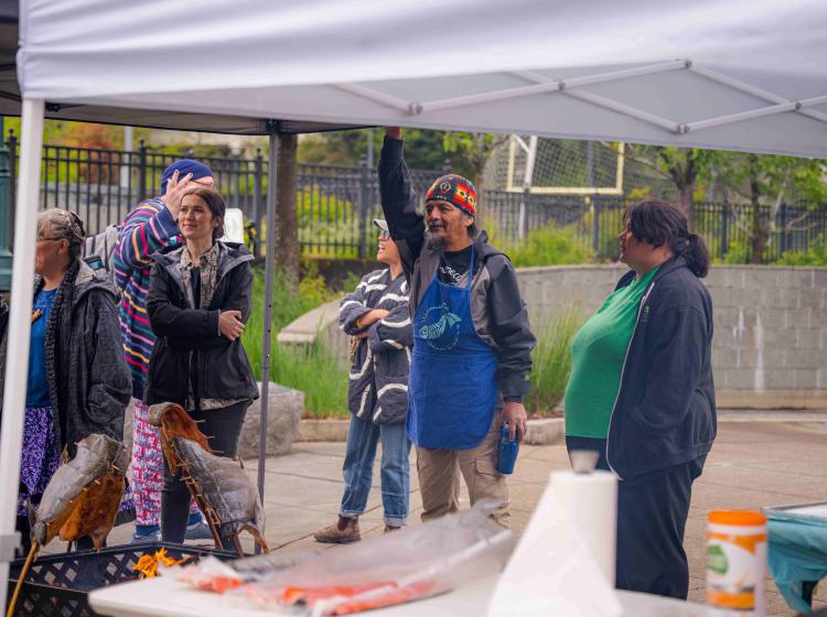 A group of people smoking fish under a canopy