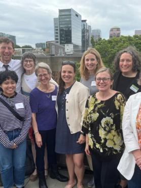 group of current and former ISS staff members face the camera on a rooftop on campus