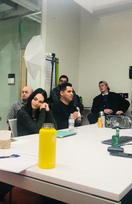 several students sitting around a small conference table taking notes or conversing