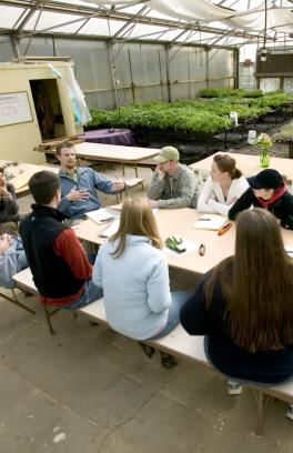 several people sitting around a table with greenhouse plants behind them