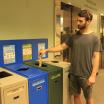 person placing a banana peel in a green bin