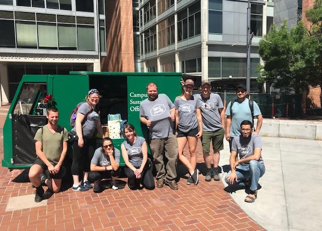 nine people standing next to electric cart labeled campus sustainability office