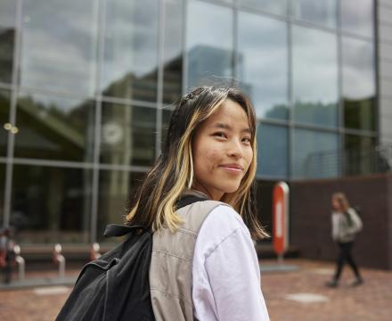 PSU student with backpack walks to class via the Urban Plaza