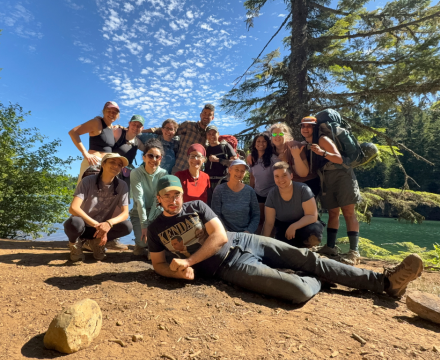 Group of PSU adventure therapy students smiling together outdoors near a forested lake
