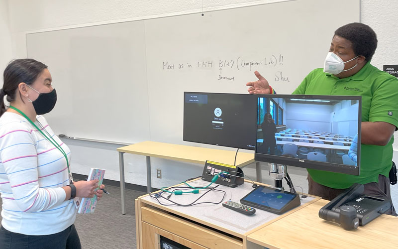 OIT employee providing a walkthrough of a classroom podium to a professor