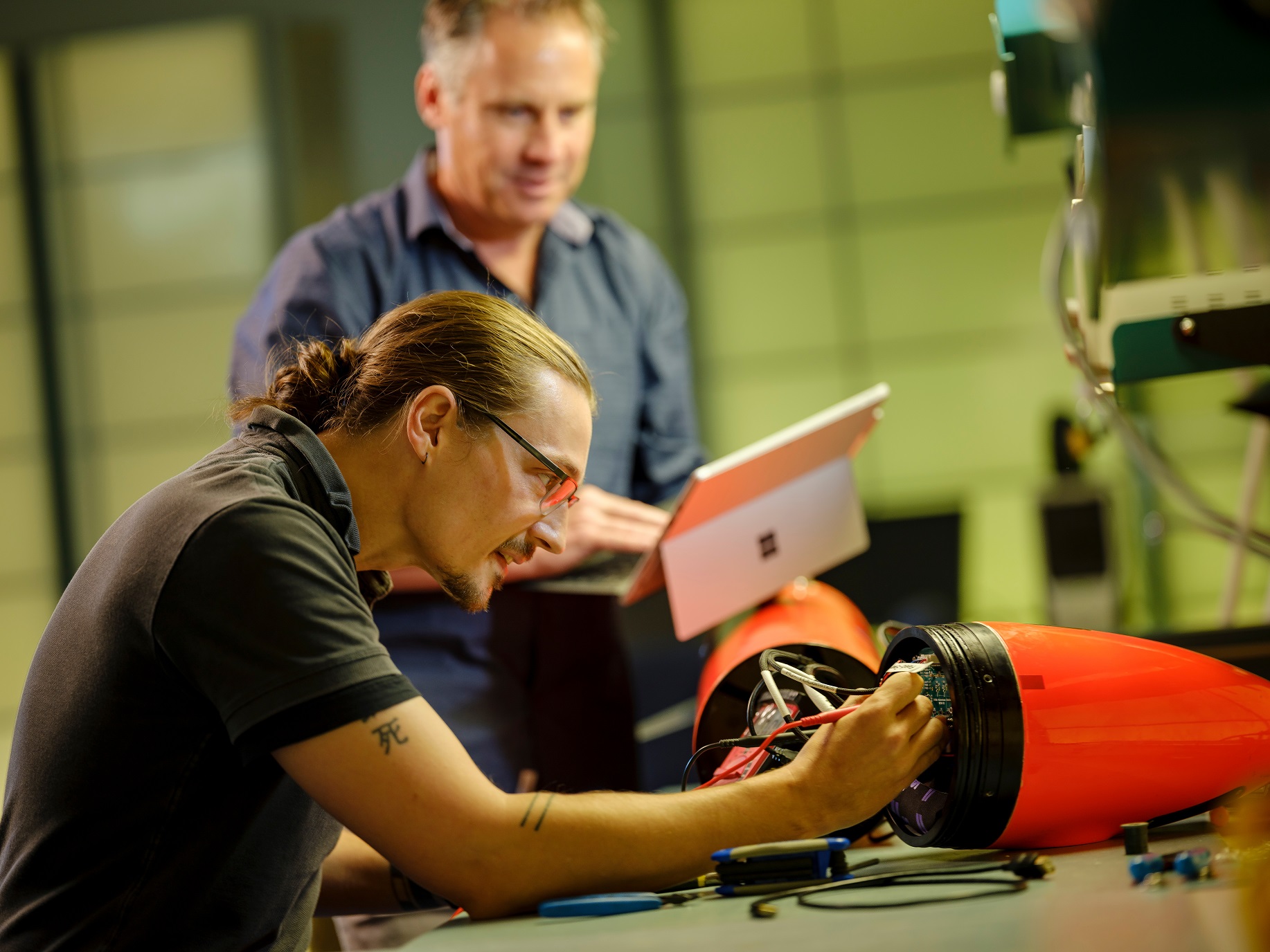 a student working on a machine while a professor provides notes
