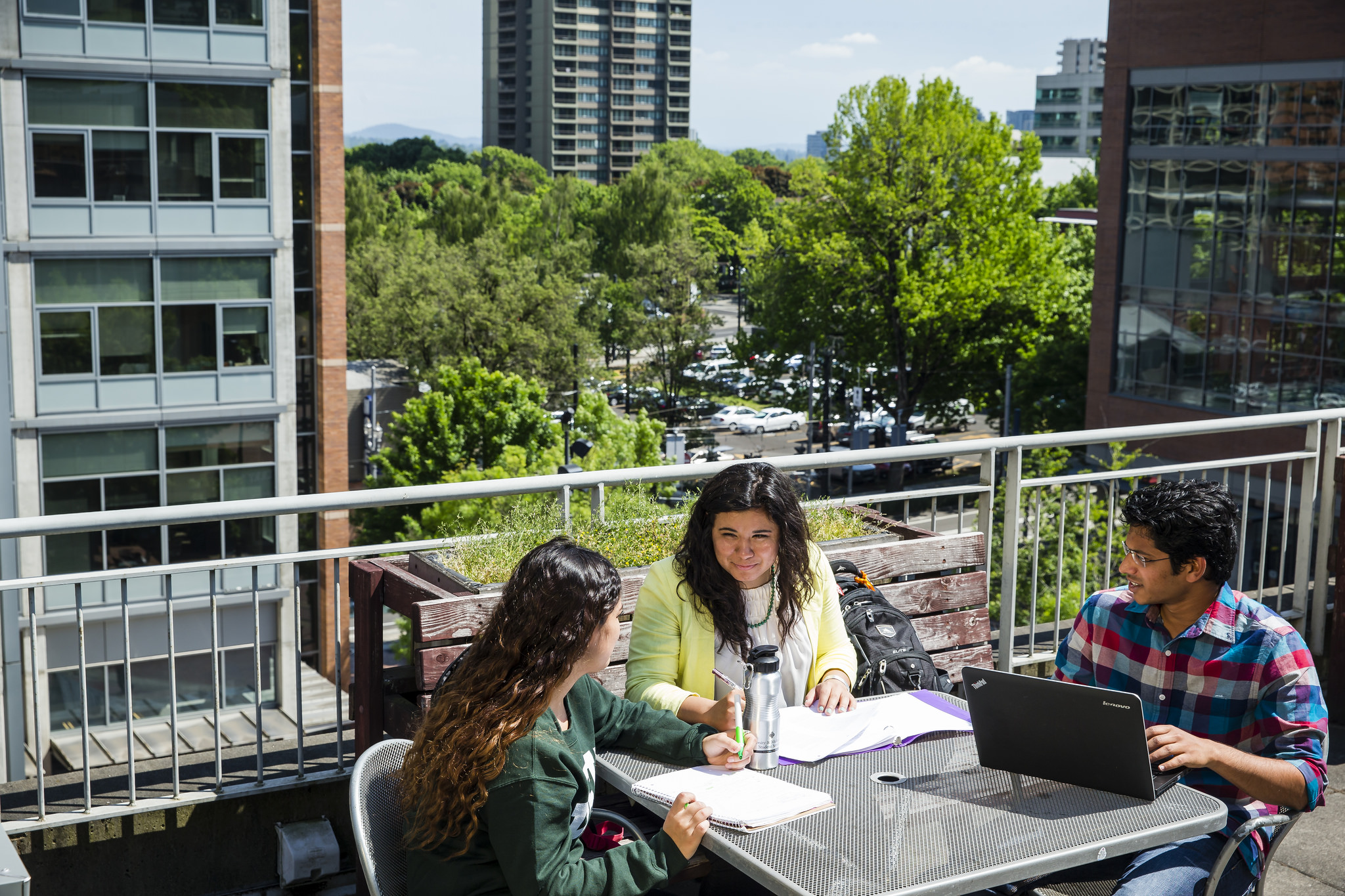 Three people, two women and man sitting outside conversing