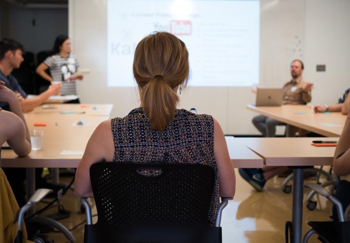 Employee with their back to the camera sitting in a chair watching a presentation