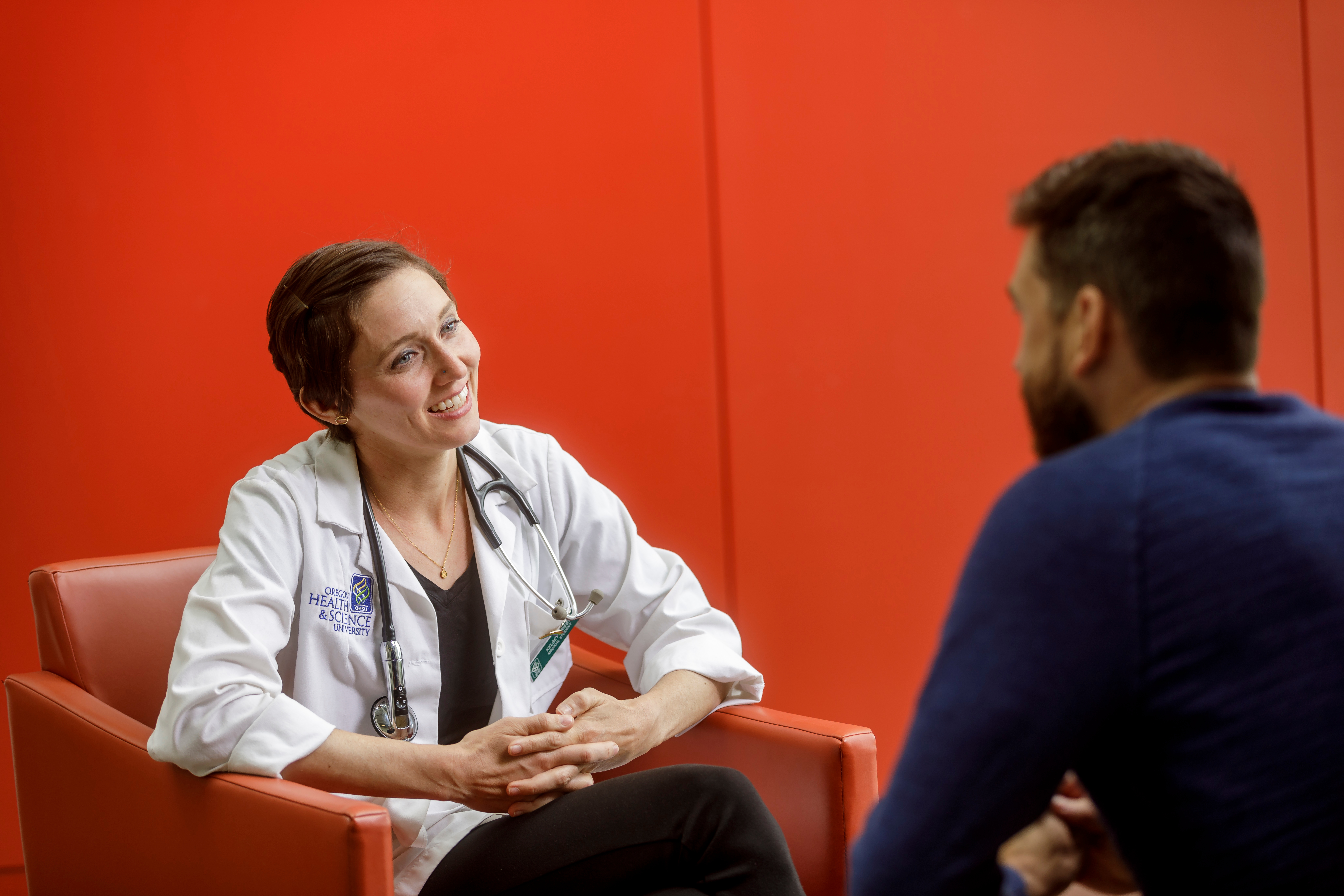 a clinician in a lap coat and stethoscope talking to a patient