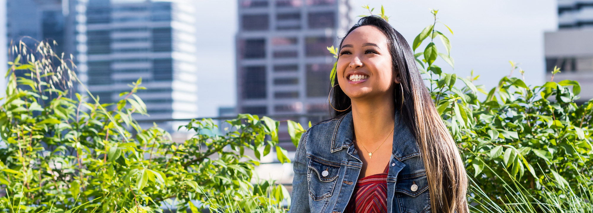 Student sitting outside in front of plants and buildings