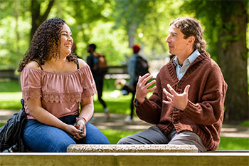 Two individuals talking on a bench in the PSU Park Blocks