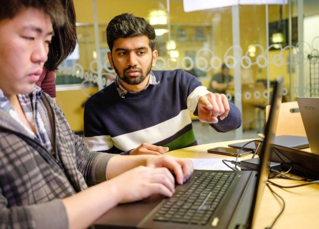 three students working together at a laptop