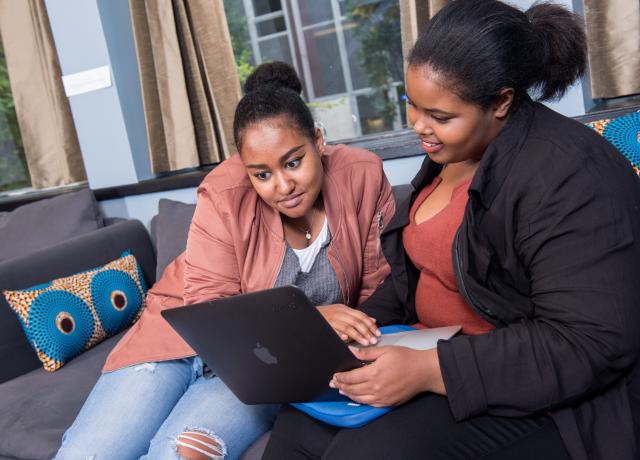 two individuals looking at a laptop screen together