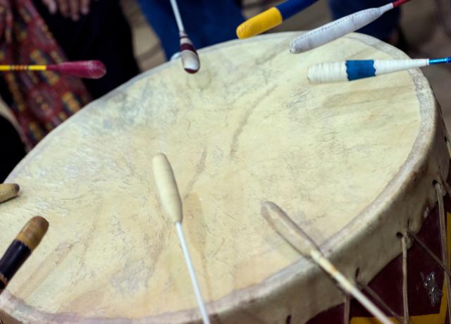 close up photo of a traditional Native America drum with several drumsticks around the drum