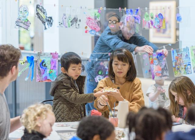 a group of children working on a craft project with an adult providing support
