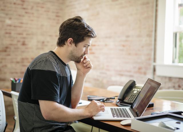 a person seated at a desk working on a laptop