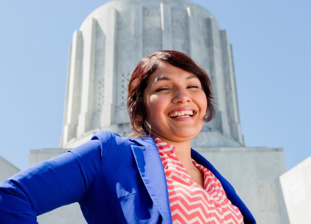a student wearing business attire stands in front of the Oregon Capital Building