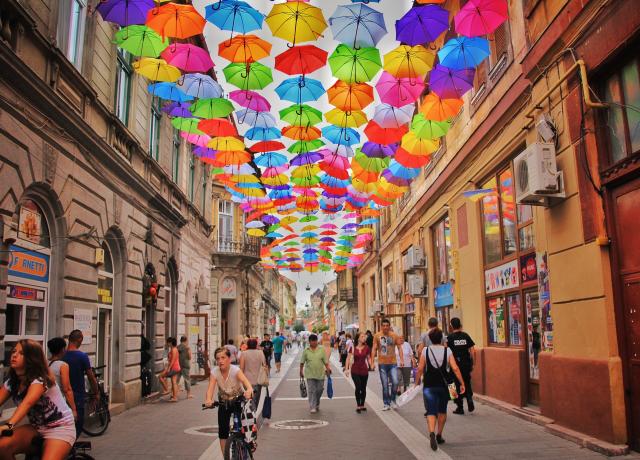a pedestrian street with colorful umbrellas hung between buildings
