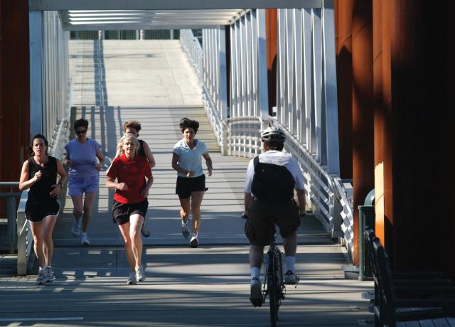 A group of people jogging across a bridge