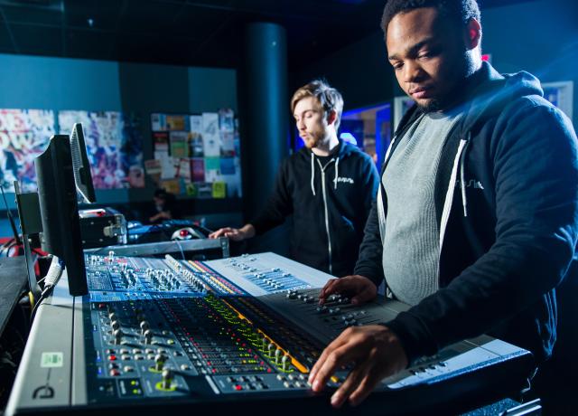 two individuals working at a music mixing board