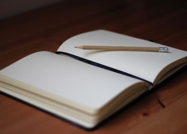 blank open notebook with a black ribbon bookmark sits on a table