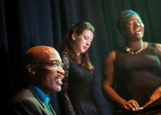 Image of faculty with two people singing behind.