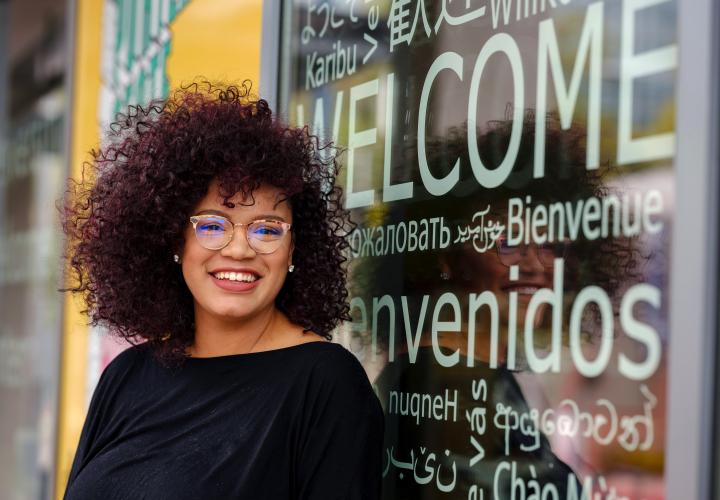student standing in front of window with welcome in multiple languages
