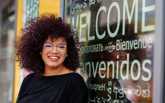 student standing in front of window with welcome in multiple languages