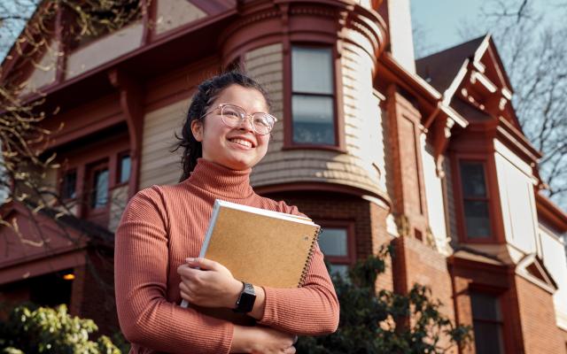 female student holds onto two spiral notebooks.