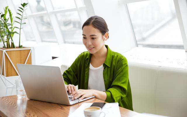 a student seated at a table working at a laptop computer