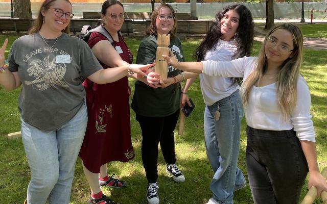 Image of students outside with a hand in center.