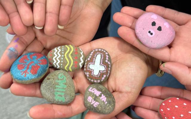 Hands holding painted rocks