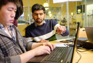 three students working together at a laptop