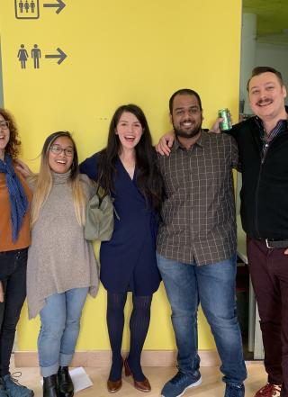 Five students stand in front of a wall