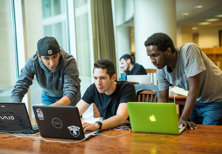 Three students in library work with their laptops