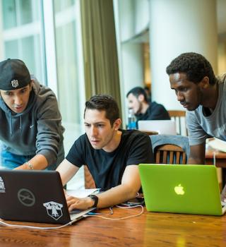 Three students in library work with their laptops