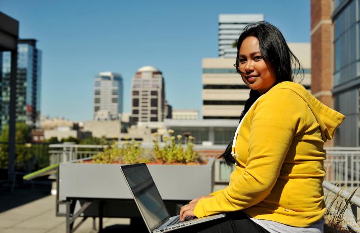 Student on laptop, overlooking skyline