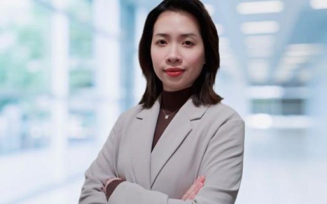 Huijun Tan stands in the foreground with her arms crossed.