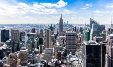 A cityscape with skyscrapers and a blue sky with white clouds