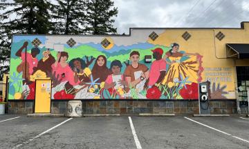 A colorful mural with nine different people on a yellow wall