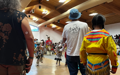 Citizens from UIR stand watching a pow wow performance.