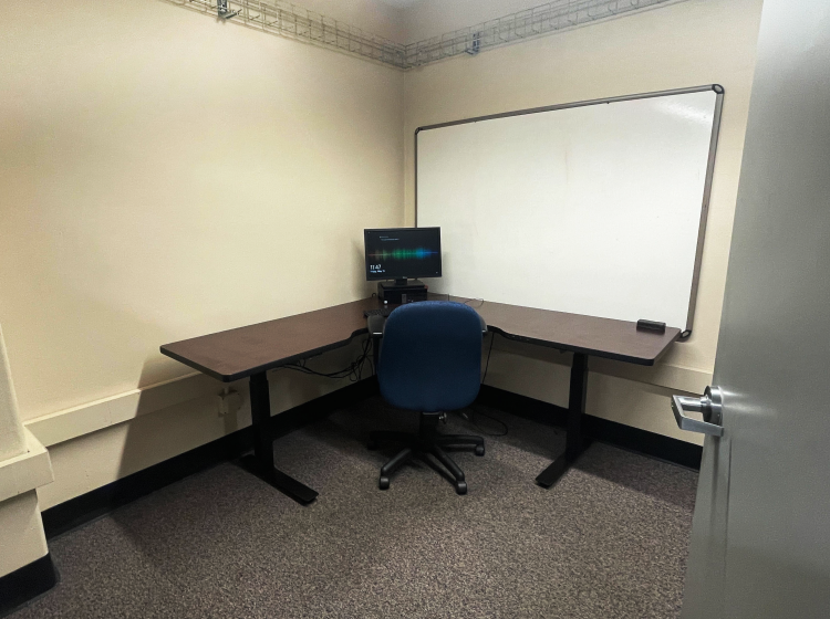 Chir with L shaped desk with a computer, and whiteboard on the wall