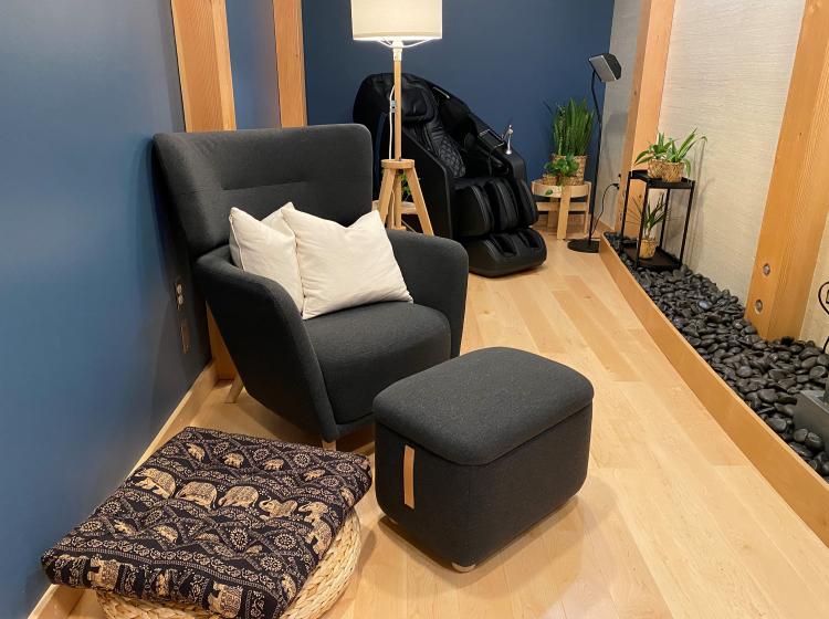 closer shot of blue arm chair with ottoman, round wicker mat with square pillow on top