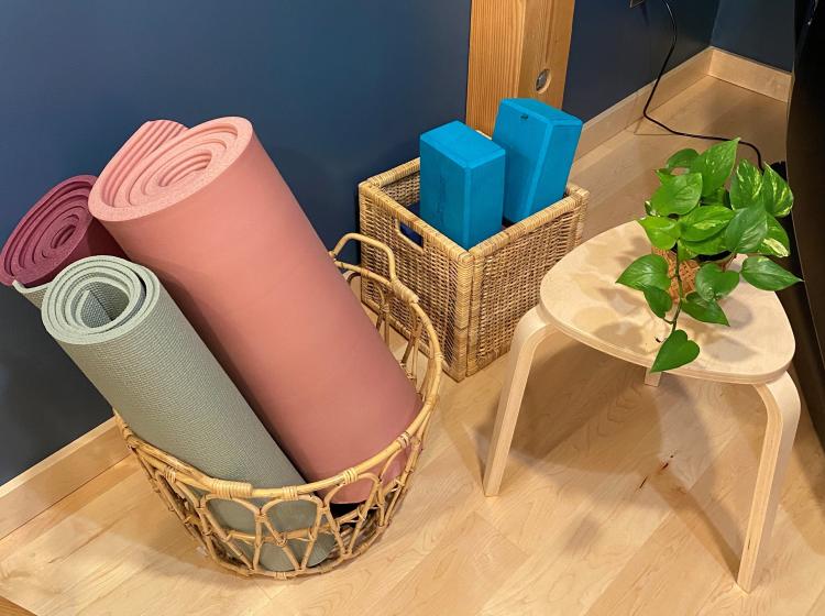 wicker basket of yoga bats, wicker box of massage blocks, little shelf table