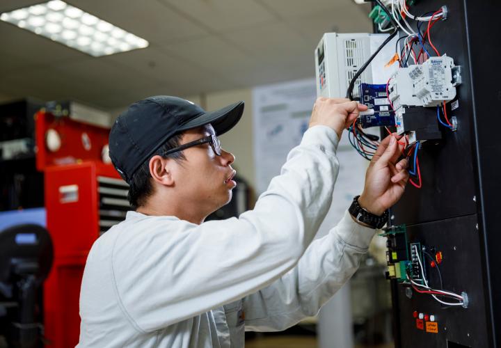 Person with ballcap in engineering lab, working on wiring
