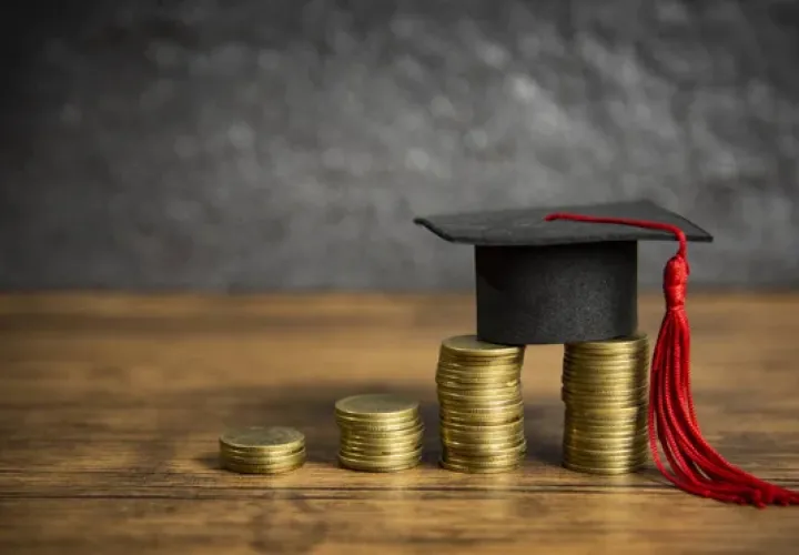 4 stacks of pennies with a graduation cap balanced on the two tallest stacks