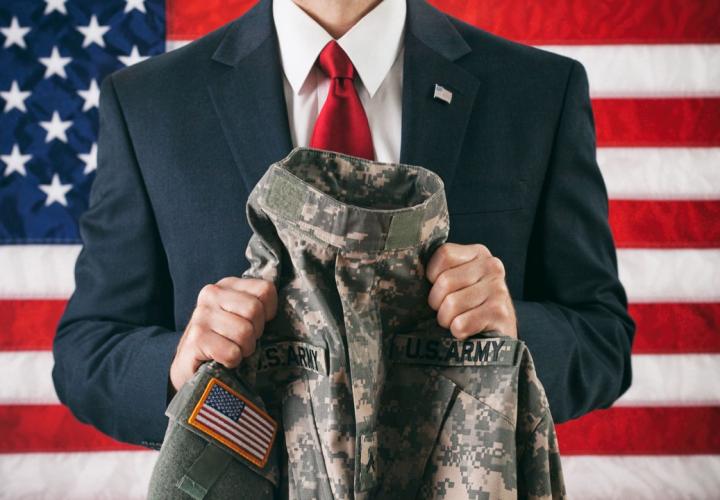 man in suit holds up mil uniform