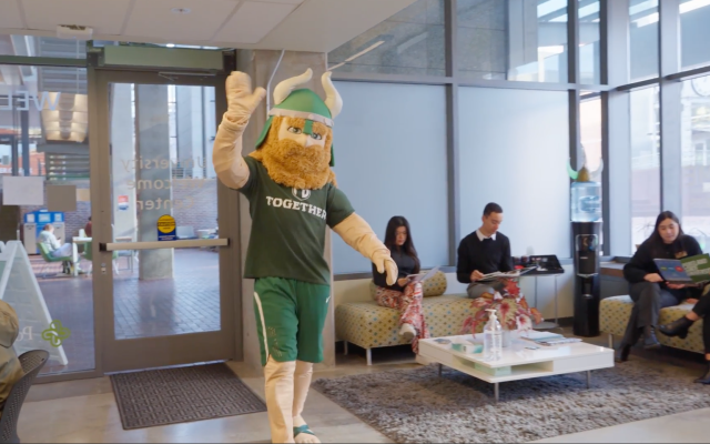 Victor E. Viking waving as he walks into the Welcome Center