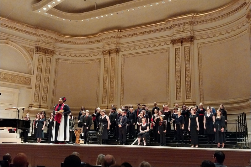 Coty at microphone with Briar behind her on Carnegie stage 