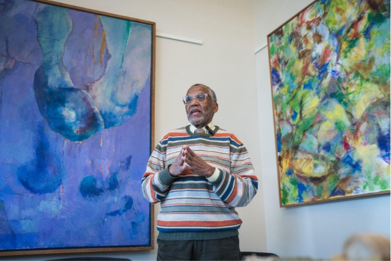 Dean Bynum in his office showing paintings